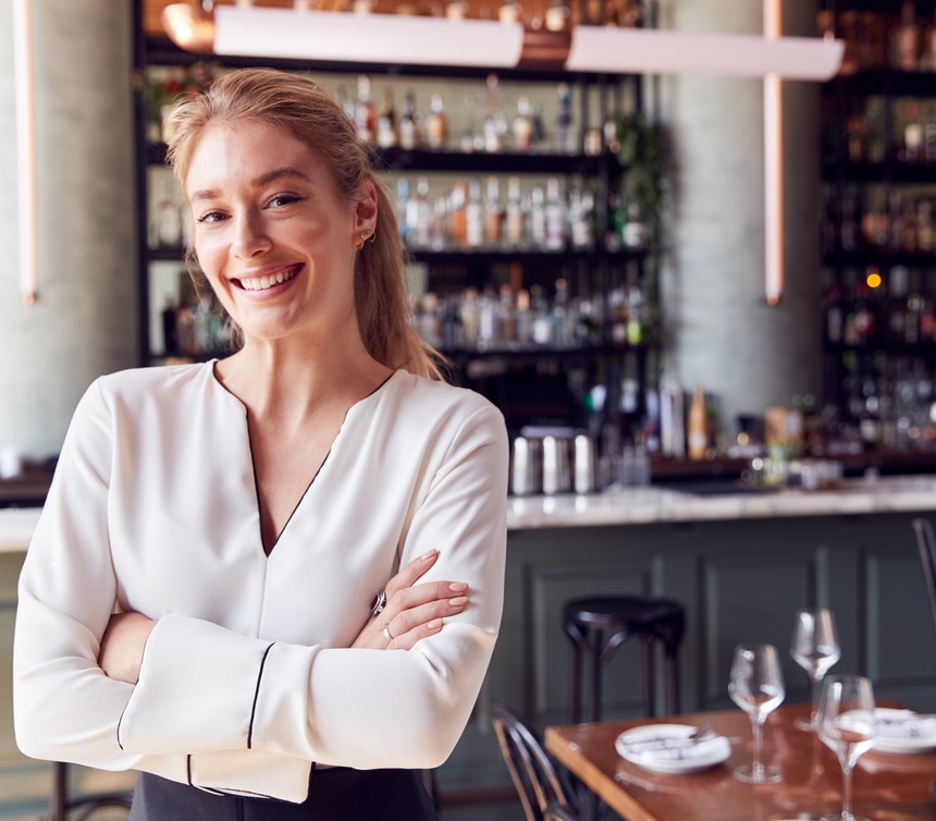 Portrait Of Confident Female Owner Of Restaurant Bar Standing By Counter