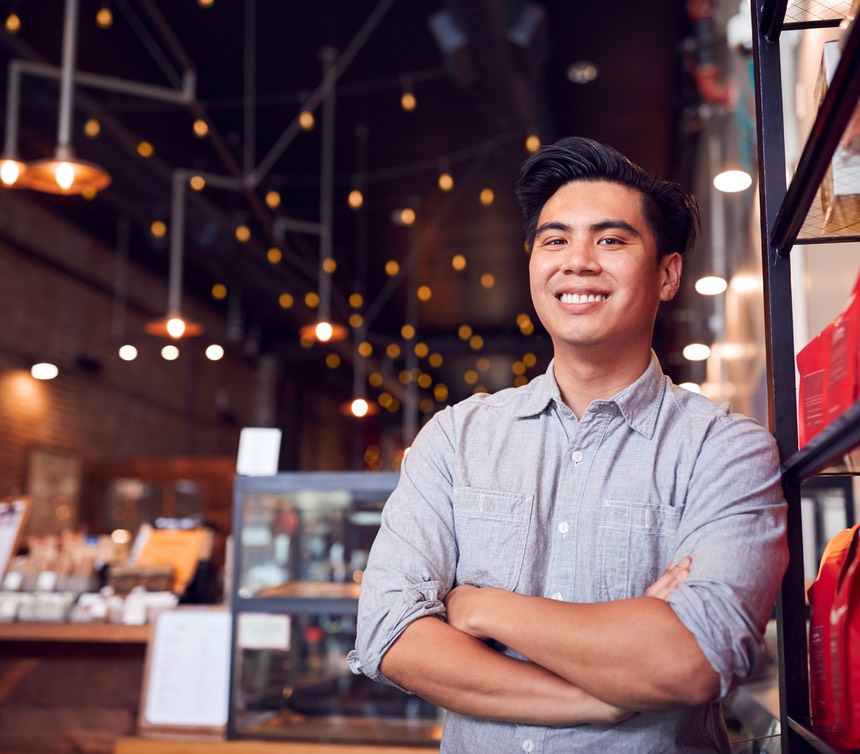 Portrait Of Male Coffee Shop Owner Standing By Counter