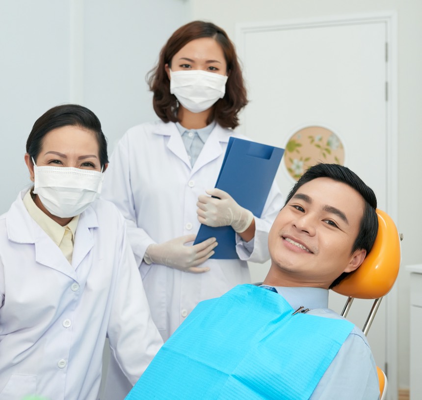 Smiling patient and doctors in dental office